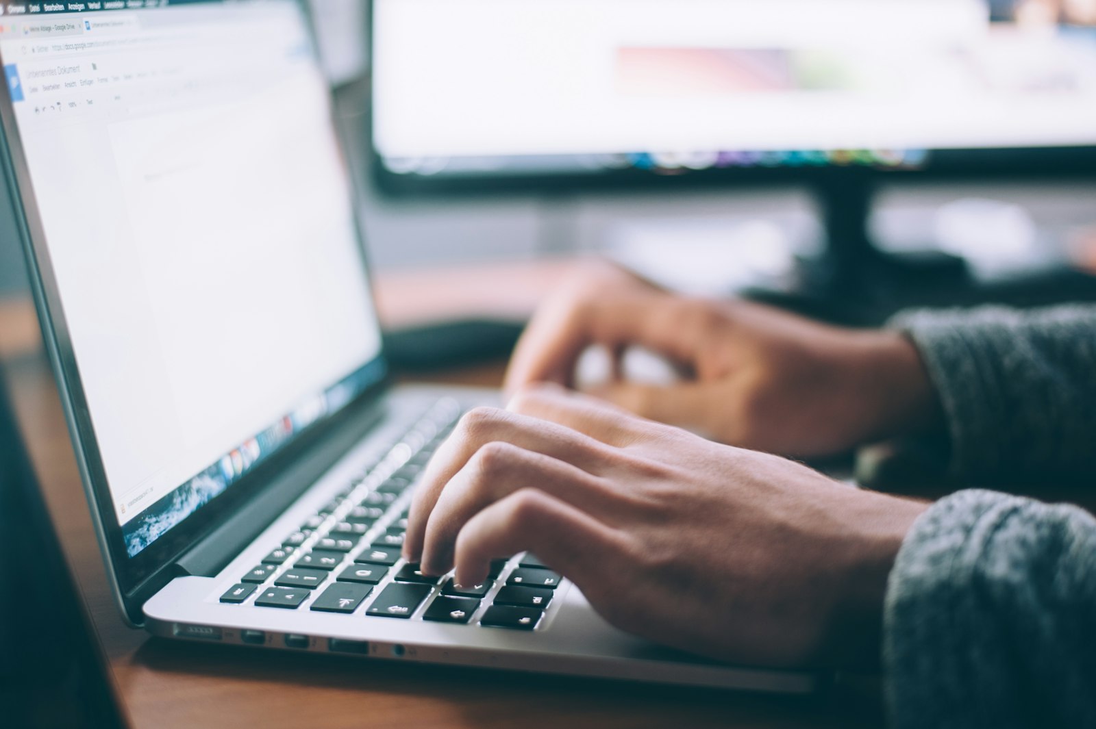 A person at a laptop with a notebook, working