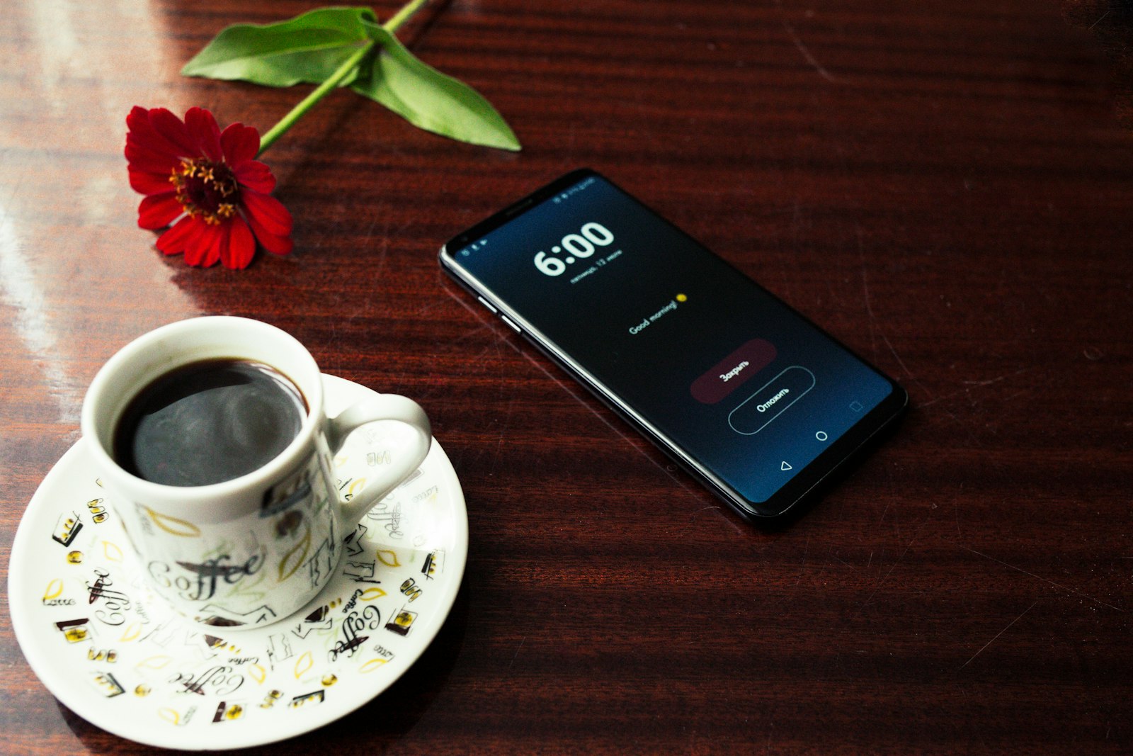 A smartphone beside a cup of coffee in the morning light