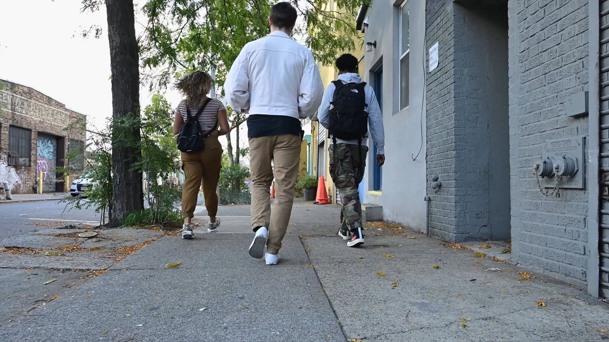 Three friends walking together along a city street.