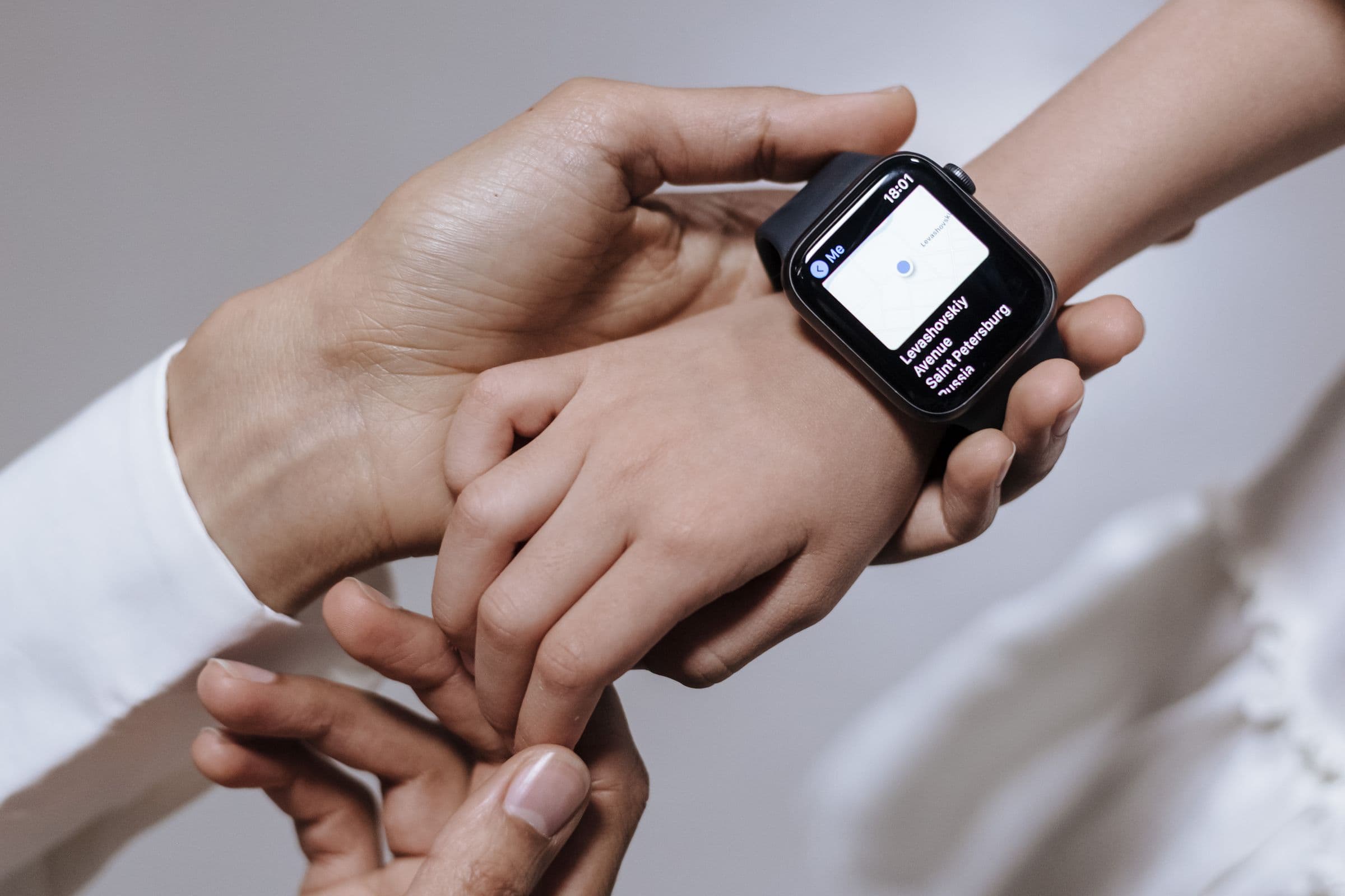 An adult holding a child's wrist, fastening a smartwatch.